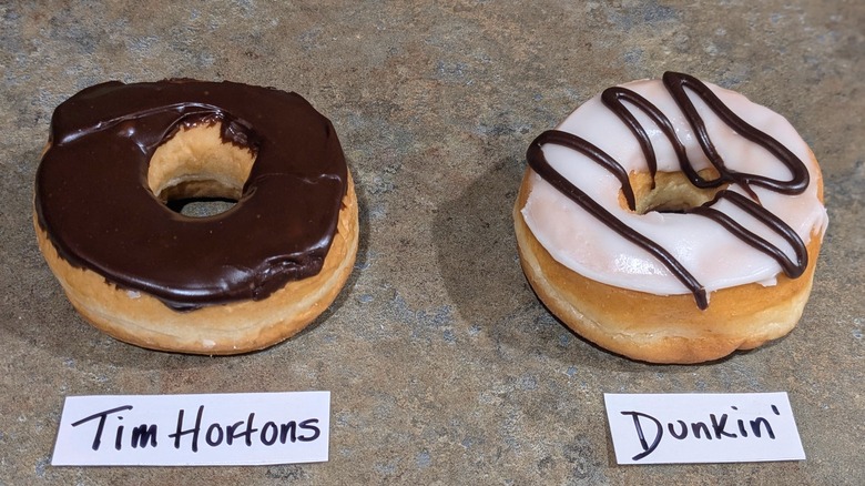 Chocolate-frosted Tim Hortons donut and vanilla-frosted Dunkin' donut with chocolate drizzle