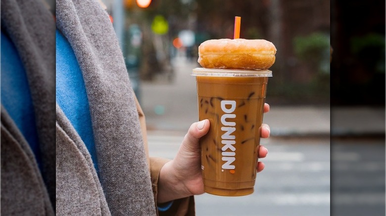 Person carrying Dunkin' iced coffee, donut