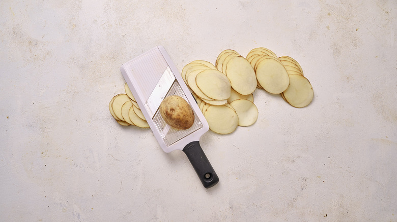 slicing potatoes on a mandolin