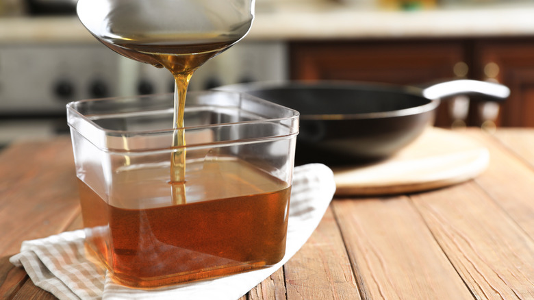 ladle pouring used oil into container