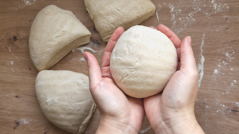 hand holding tight pizza dough ball