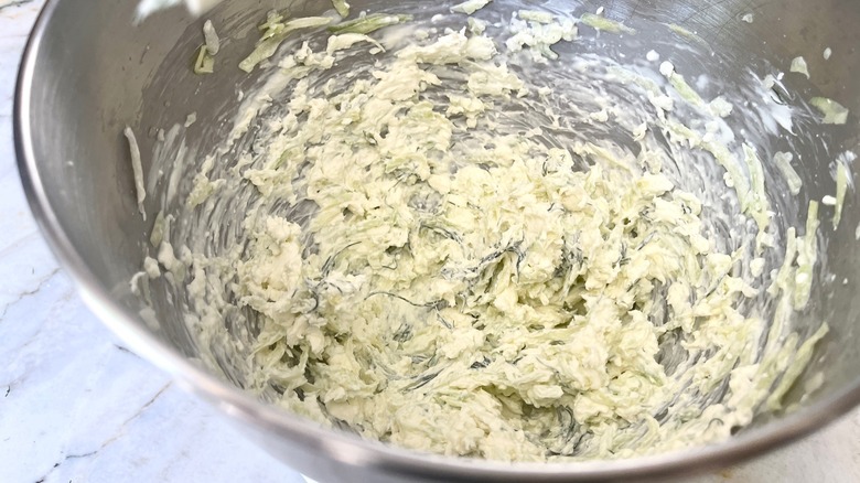 A metal mixing bowl containing the ingredients for Benedictine spread