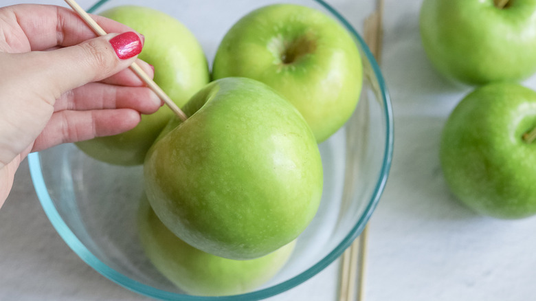 hand holding green apple with skewer