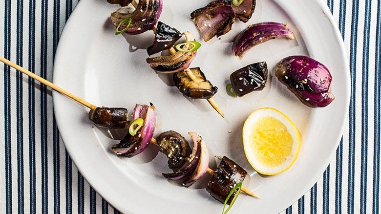 eggplant and onion skewers with lemon wedge