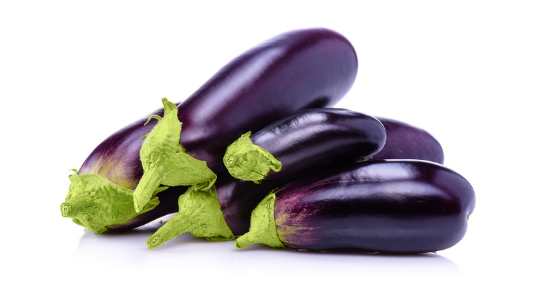 pile of purple eggplants on white background