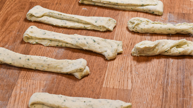 folding strips of bread dough on wood board