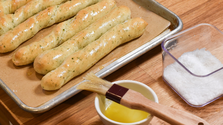 brushing breadsticks with butter