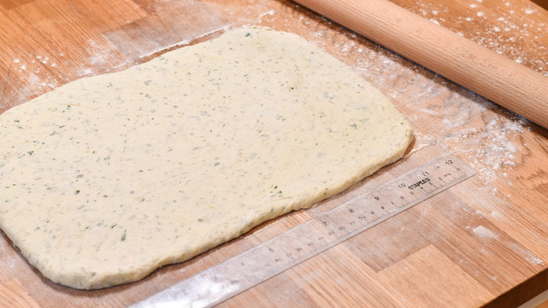 rolling dough into rectangle on wood board