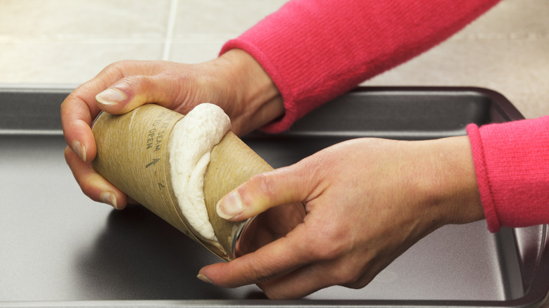 Hands opening can of biscuit dough