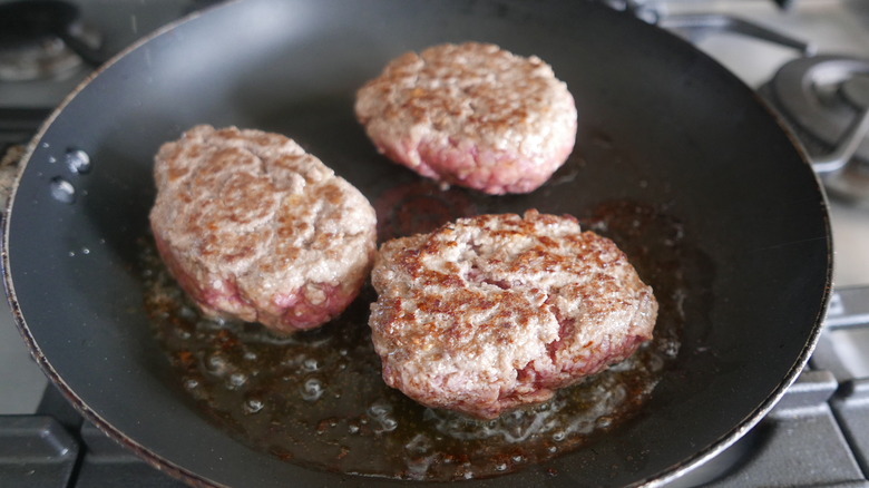 beef patties cooking in skillet