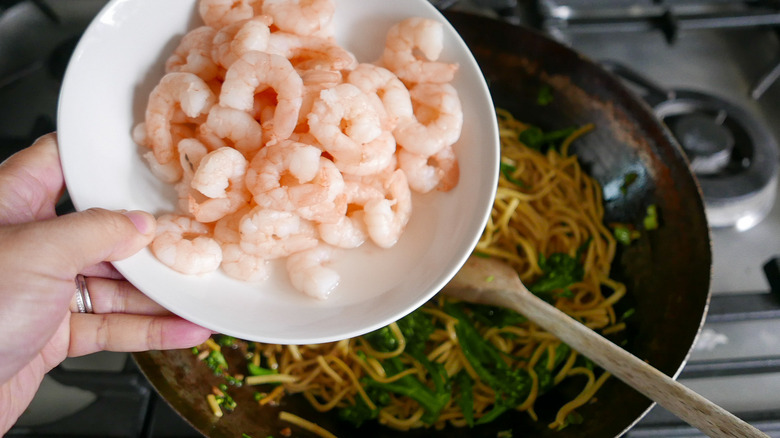 adding shrimp to wok