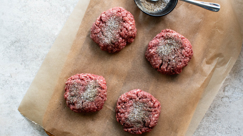 four burger patties with seasoning