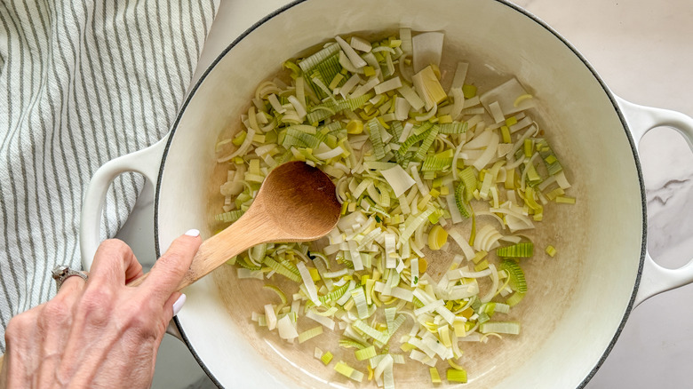 hand stirring leeks in pot