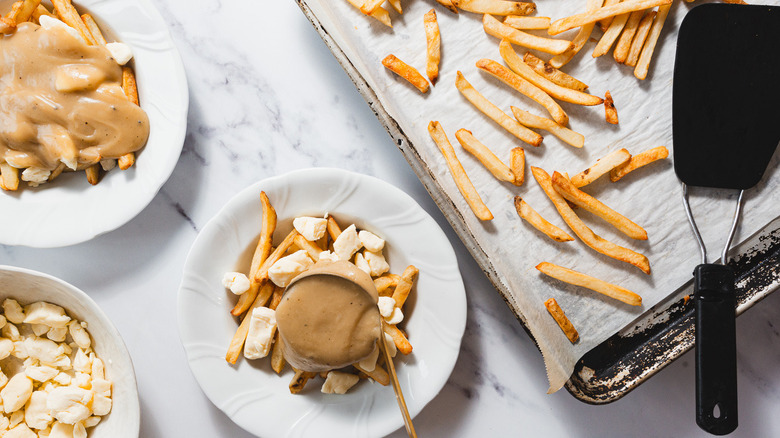 Adding gravy to plate of poutine with curds