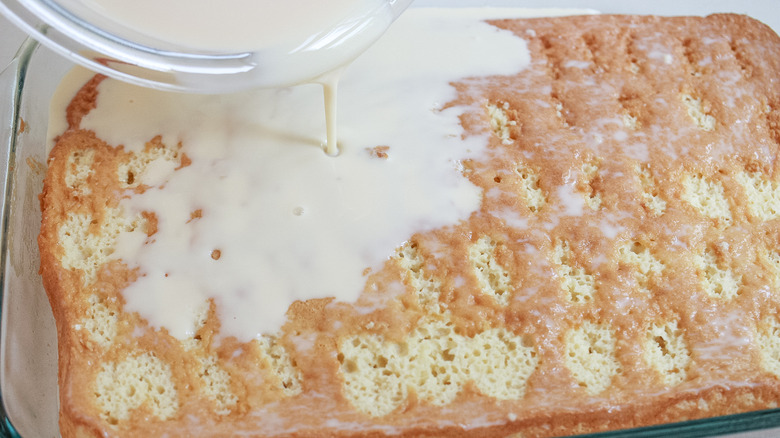 Pouring milk mixture over cake