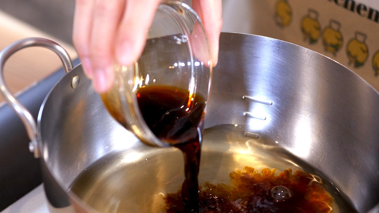 pouring soy sauce into pot 