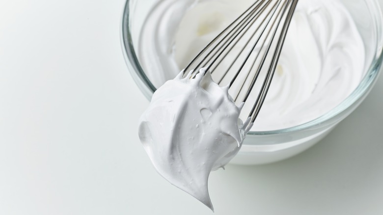 Whipped egg whites with stiff peak on whisk