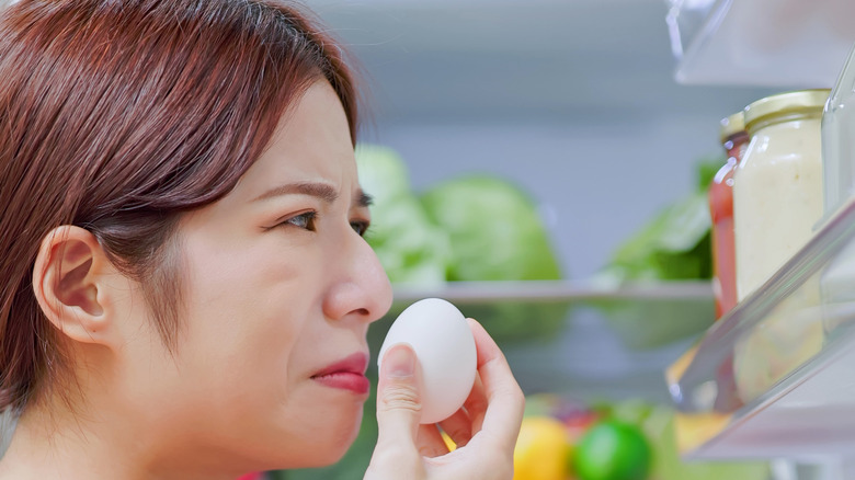 person smelling an uncracked egg