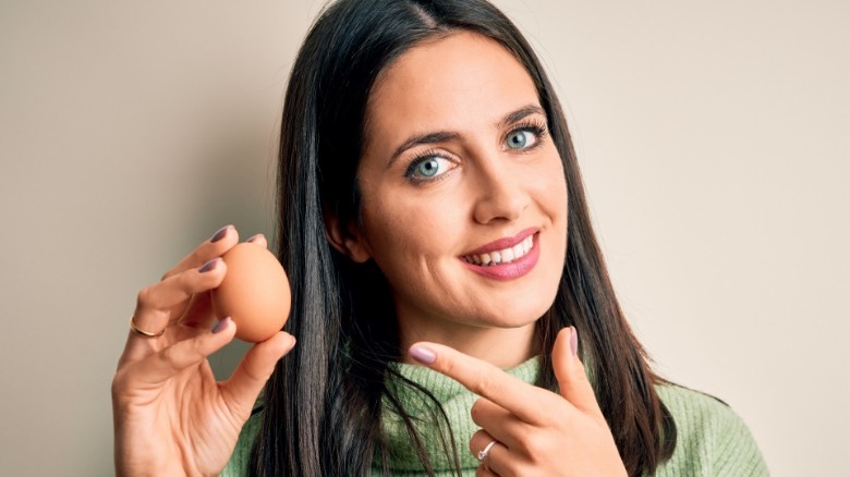 A woman holds/points to egg