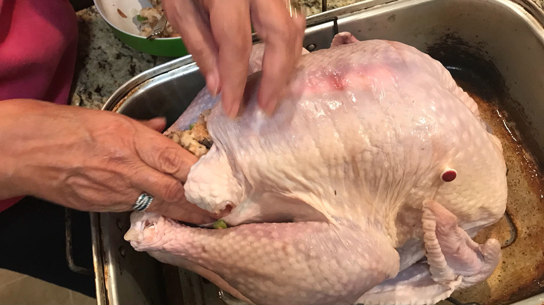 hands stuffing a turkey