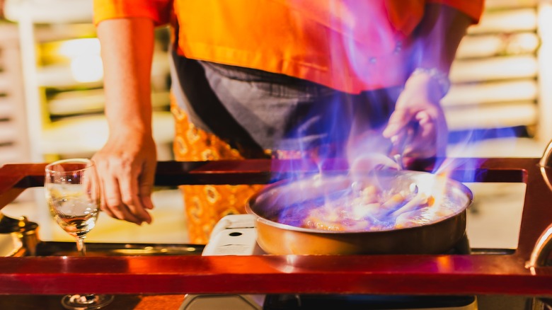 person cooking flambéed dish