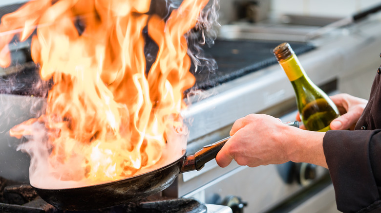 person flambéing with bottle