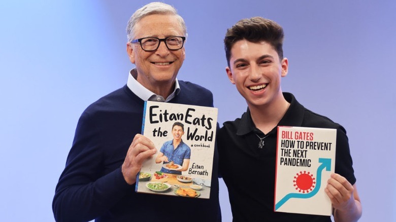 Eitan Bernath and Bill Gates holding each other's books