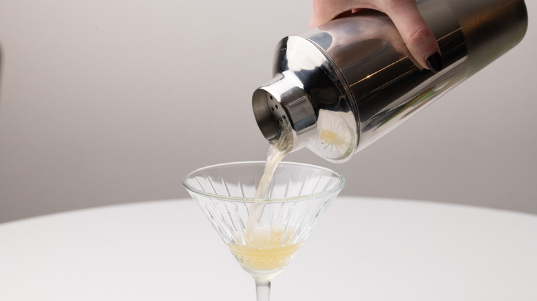 pouring drink through cocktail strainer