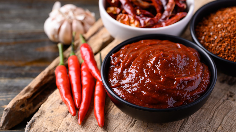 Gochujang beside whole and ground peppers