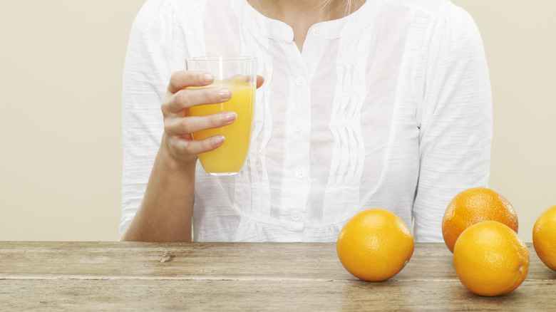 woman holding orange juice glass