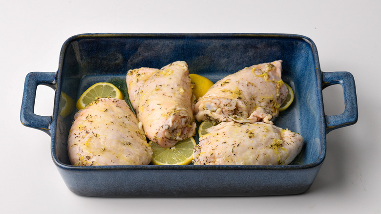 raw lemon marinated chicken thighsin baking pan