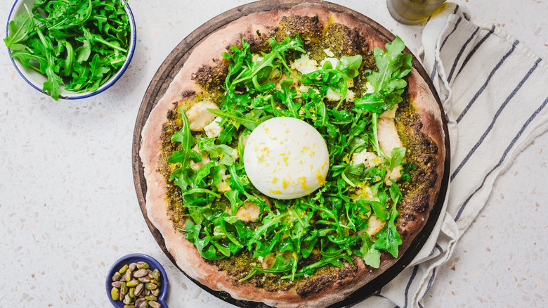 Pizza with arugula, pistachios and napkin around
