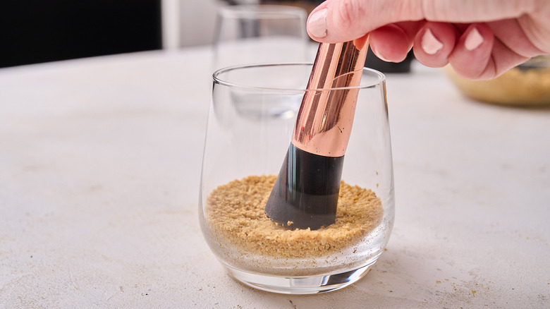 pressing graham cracker into glass