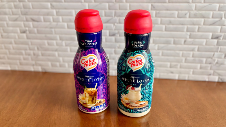 Two Coffee-Mate creamers sitting on a wooden table with white brick in the background