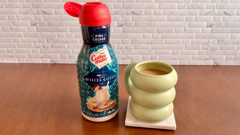 Coffee Mate pina colada flavored creamer bottle next to cup of coffee