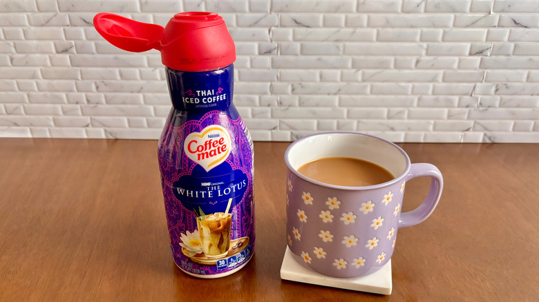 Coffee Mate Thai iced coffee flavored creamer bottle next to cup of coffee