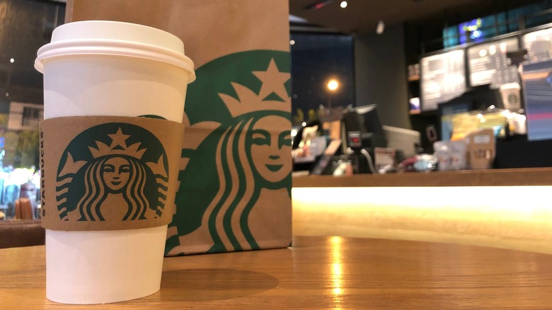 A paper Starbucks cup and bag on a counter