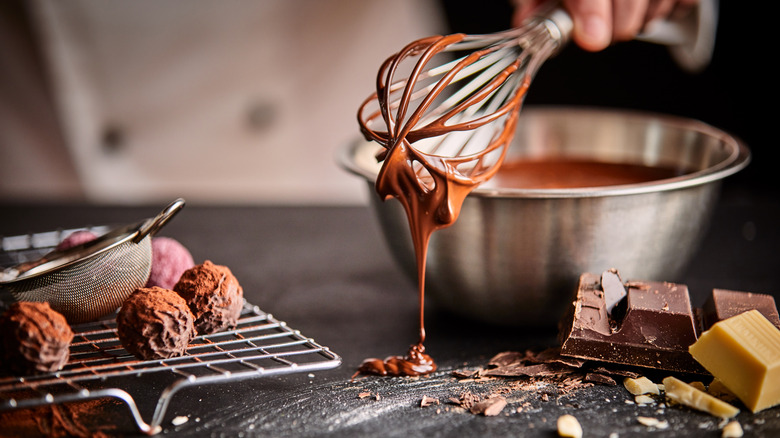 Chocolate dripping from a whisk next to truffles 