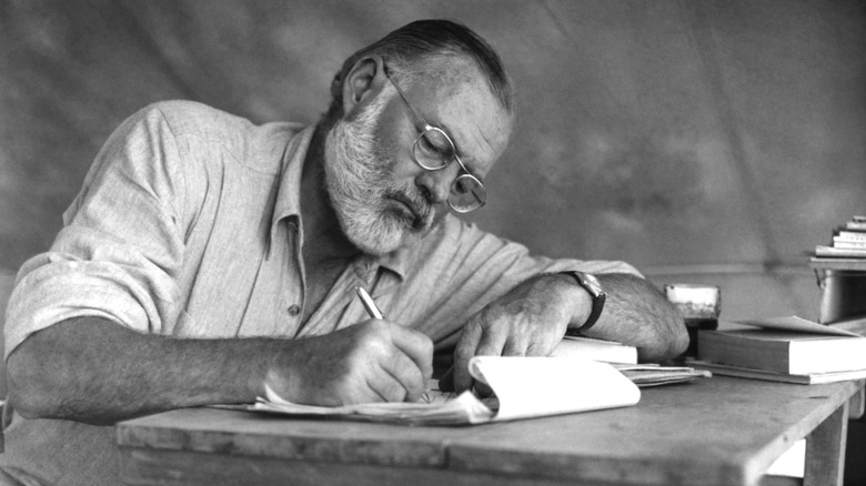 Ernest Hemingway writing at a desk