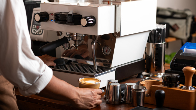 barista using an espresso machine inside cafe