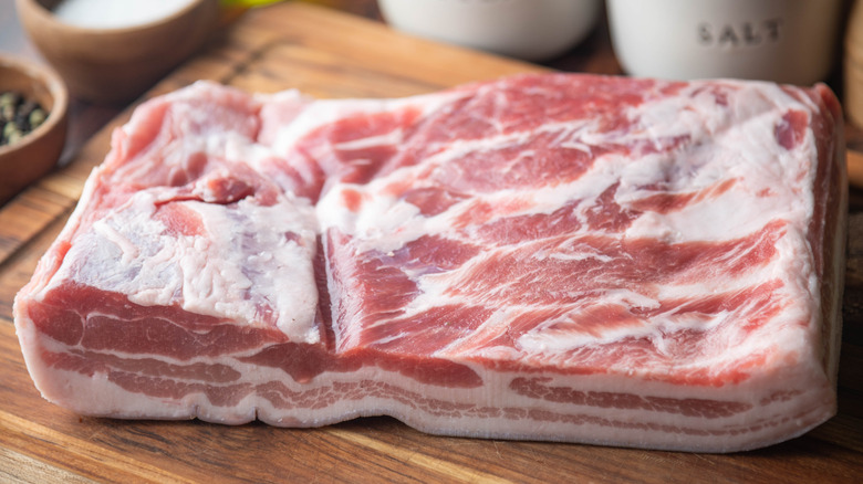 slab of raw pork belly on wooden board