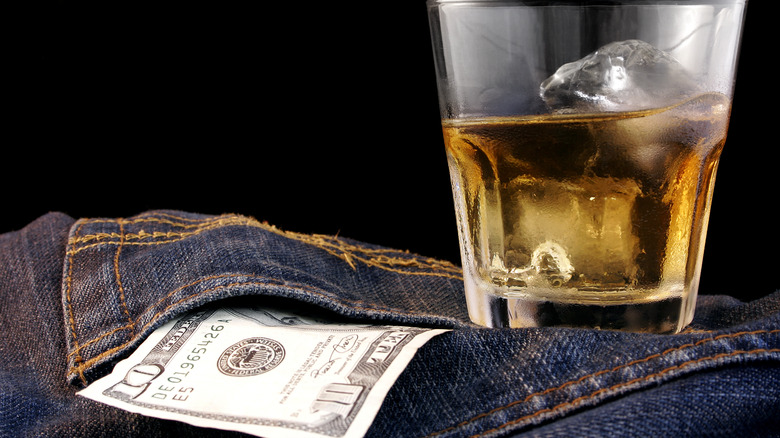 glass of liquor with ten dollar bill