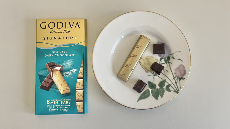 A Godiva sea salt chocolate bar is shown on a plate next to the packaging.