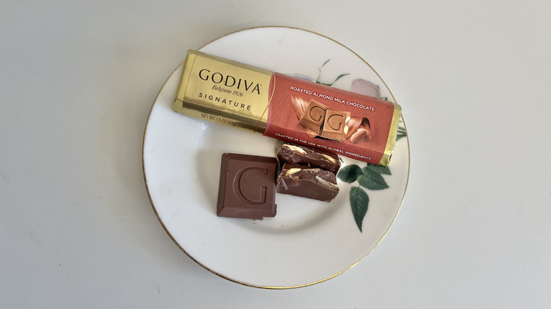 A Godiva roasted almond milk chocolate bar is shown on a plate.