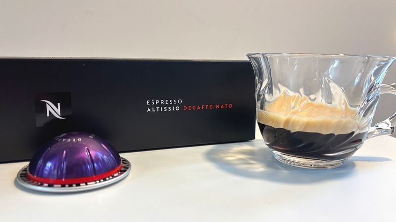 Clear teacup on Nespresso Altissio Decaffeinato next to box and pod on white table