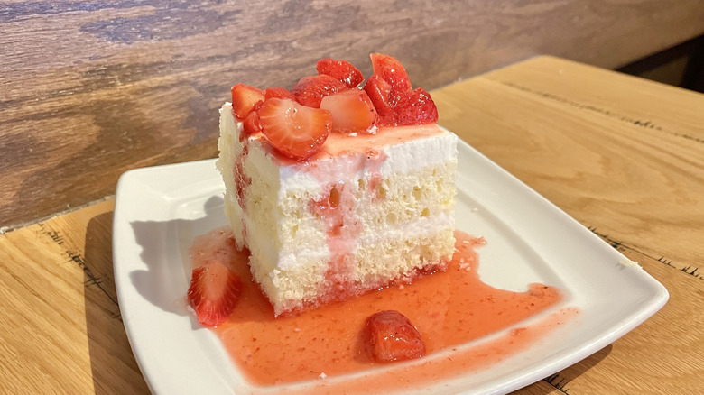 A slice of Olive Garden's strawberry sponge cake with sauce on a white plate