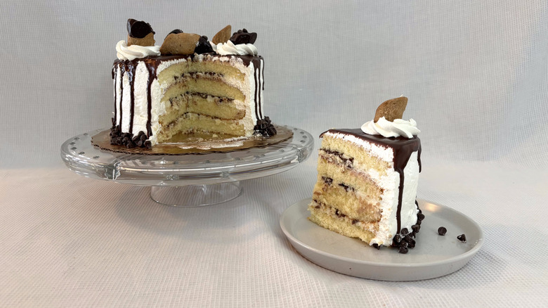 Publix cannoli supreme cake on glass cake stand and slice on white plate with white background