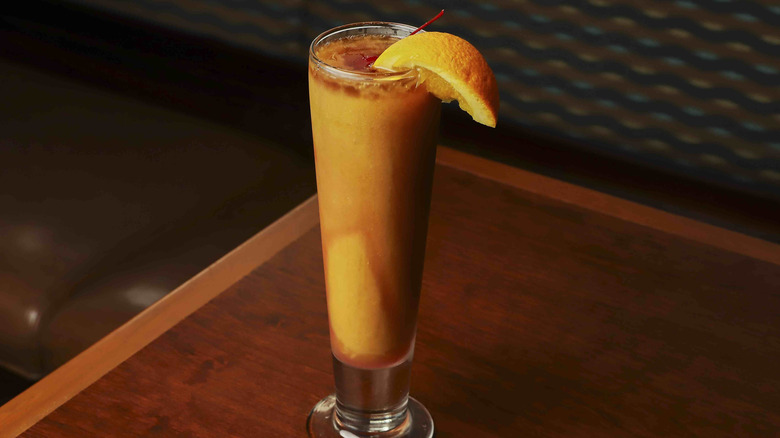 Tall, orange blended drink on table