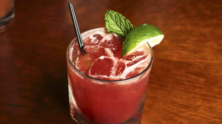 Red drink with mint and lime garnish