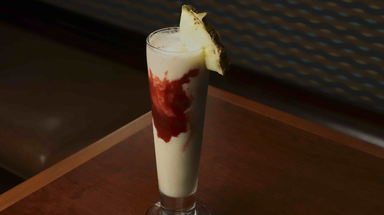 White and red striped cocktail in tall glass
